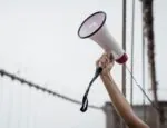 An arm holding a megaphone aloft.