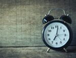 A black alarm clock on a textured background.
