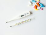 Thermometers and a collection of pills on a white background.