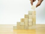A hand stacks a block on top of a tower of blocks.
