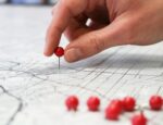 A person placing a pin on a map.