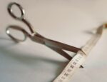 Silver scissors poised to cut measuring tape.